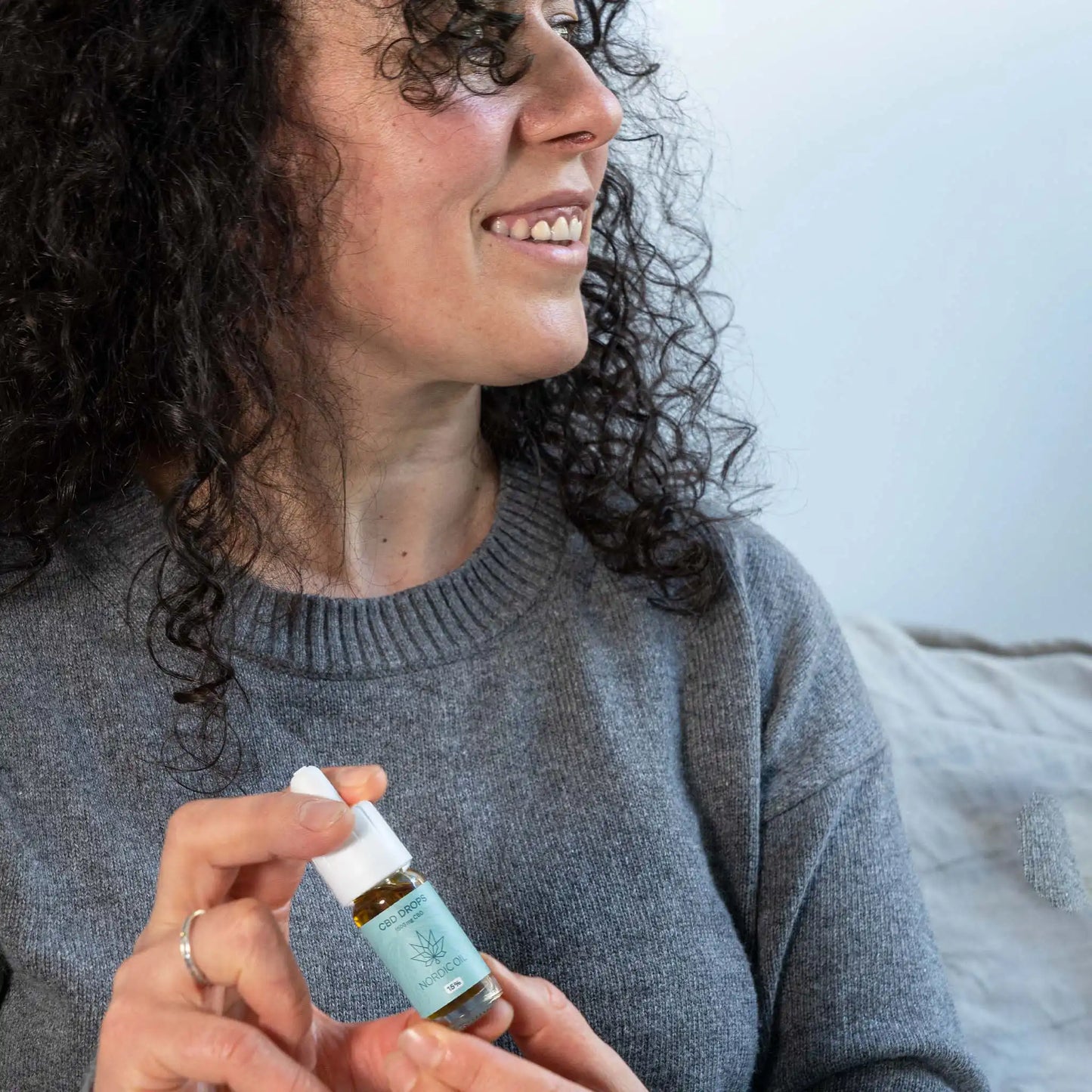 een lachende vrouw houdt de CBD olie in haar handen