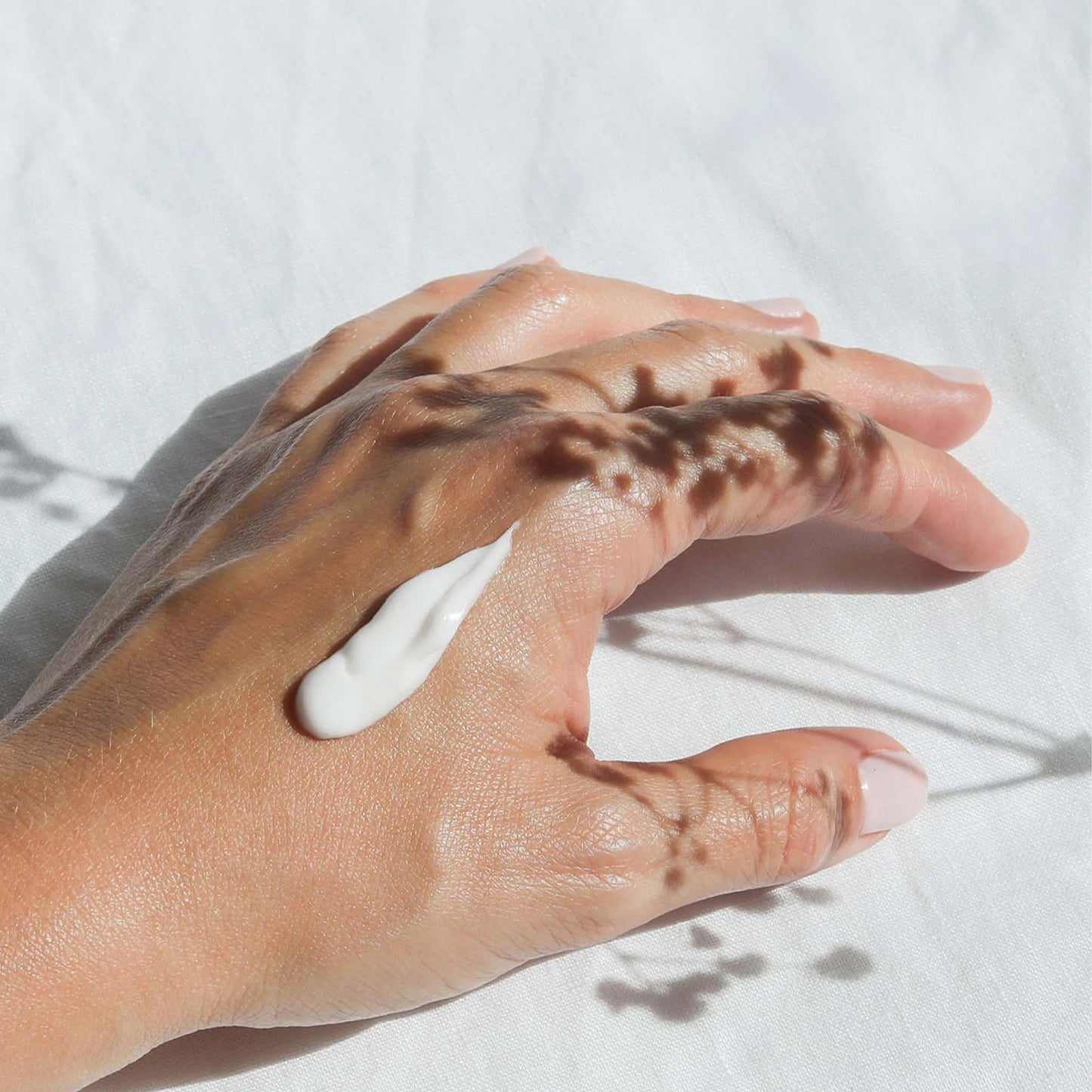 Een klodder Nordic Cosmetics handcrème zit op de hand van een vrouw.