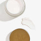 Een open verpakking en het deksel van de Nordic Cosmetics nachtcrème liggen naast een klodder van deze crème.