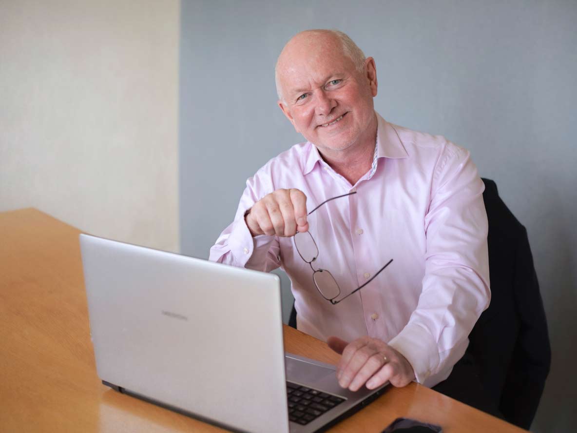 Expert Tony Reeves achter een laptop aan het glimlachen