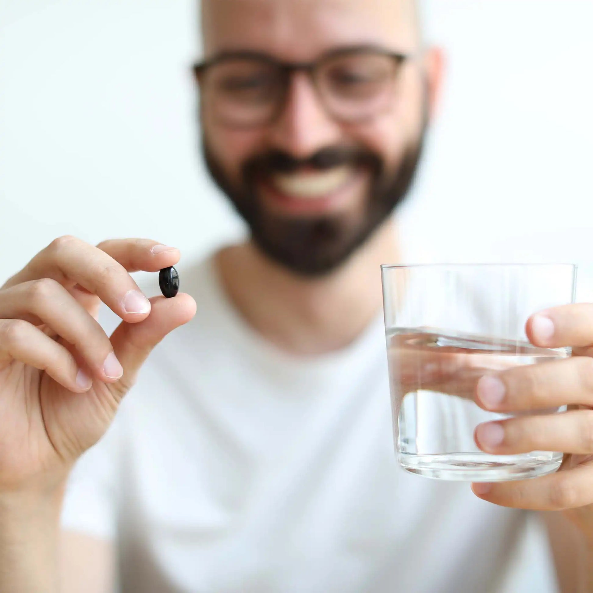 een klant houdt een glas water en een zachte gelatinecapsule in zijn handen